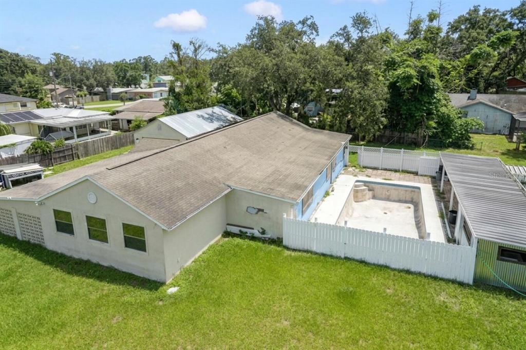 A living room features a beige sectional, a blue door, a television, and wood flooring — 11735 MARJORY AVENUE, TAMPA, FL