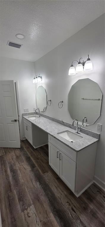 A bathroom features a double vanity with white cabinets, marble-look countertops, and two wall mirrors — 350 NE 20TH TERRACE, GAINESVILLE, FL