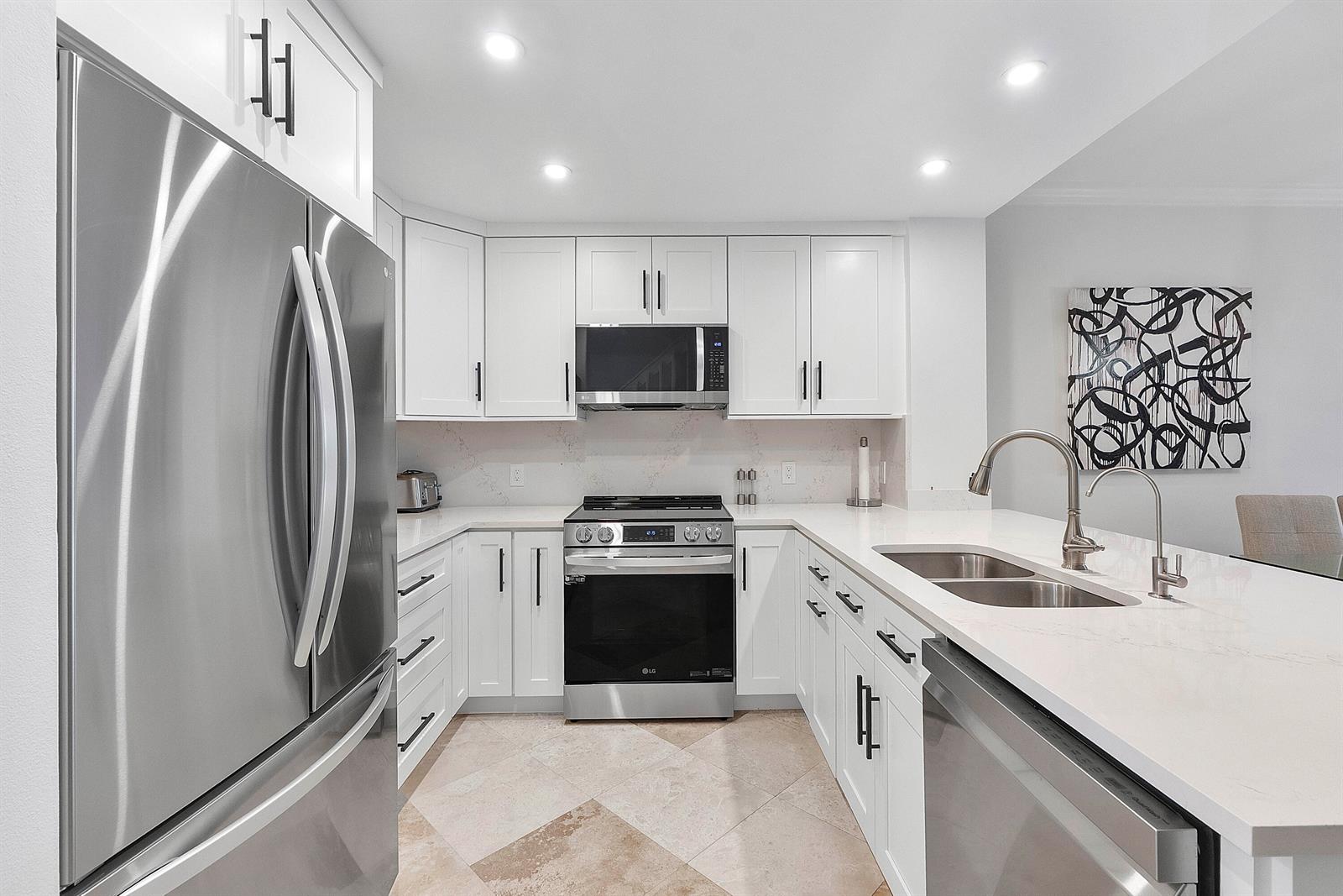 A modern kitchen features white cabinetry, stainless steel appliances, and a white quartz countertop — 3596 S Ocean Boulevard # 102, Highland Beach FL 33487, HIGHLAND BEACH, FL