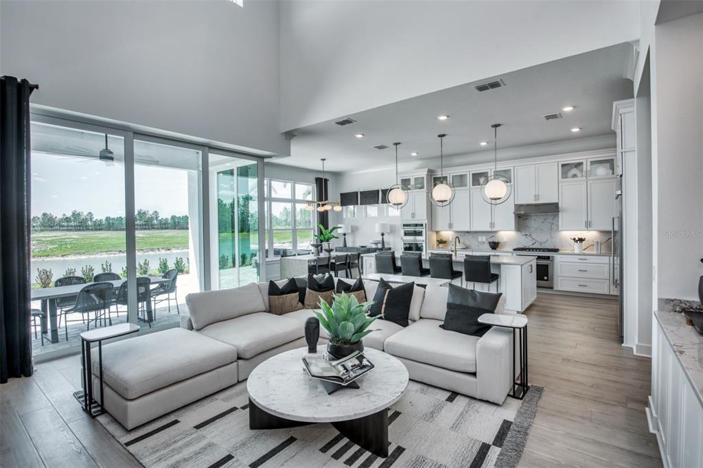 A modern open-concept living room and kitchen featuring white cabinetry, a sectional sofa, and patio — 35176 COHAGEN TRAIL, ZEPHYRHILLS, FL