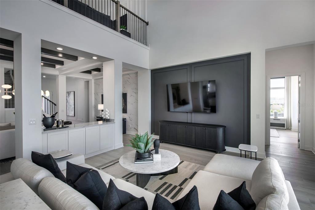 A modern living room features a dark accent wall with a mounted television and white furniture — 35176 COHAGEN TRAIL, ZEPHYRHILLS, FL