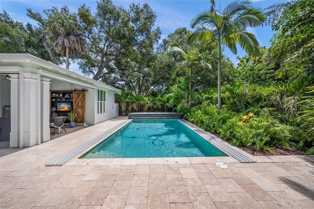 A rectangular swimming pool sits on a stone patio next to a white outdoor living space — 2440 ARLINGTON STREET, SARASOTA, FL
