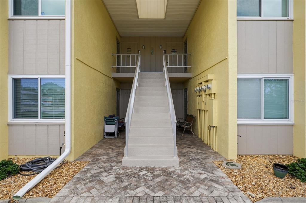 An exterior view of a two-story apartment building entrance with a central concrete staircase — 101 LOUELLA LANE UNIT 2, NOKOMIS, FL