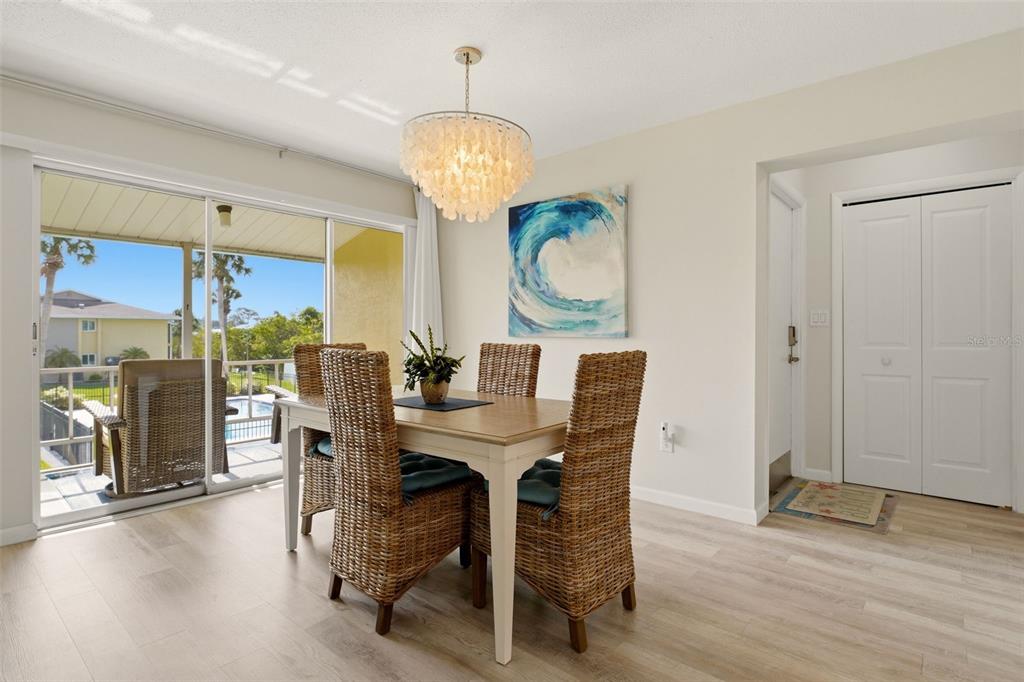 A dining room features a wicker chair set, a shell chandelier, and a sliding glass door — 101 LOUELLA LANE UNIT 2, NOKOMIS, FL