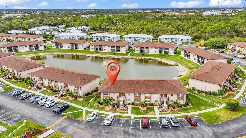 An aerial view shows a multi-story apartment building complex surrounding a central pond — 25100 SANDHILL BOULEVARD UNIT 201, PUNTA GORDA, FL