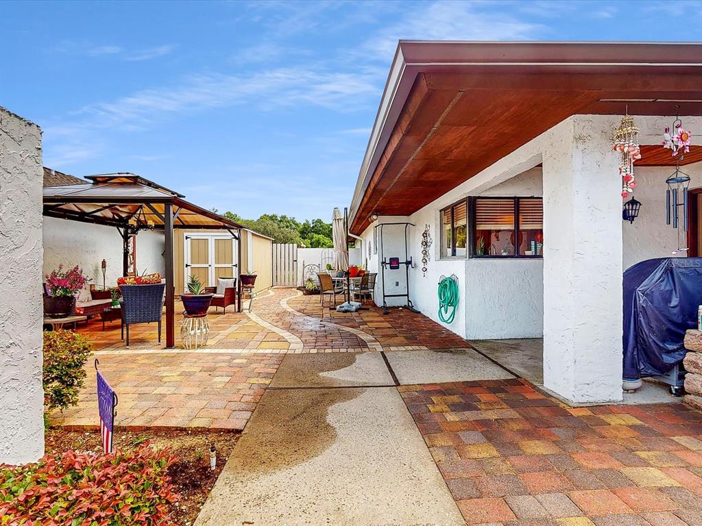 A paved patio area features a covered gazebo, a storage shed, and a house exterior — 111 TUXFORD DRIVE, HAINES CITY, FL
