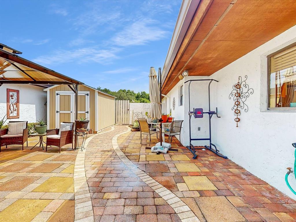 A paved patio features a curved walkway, outdoor seating, a storage shed, and exercise equipment — 111 TUXFORD DRIVE, HAINES CITY, FL