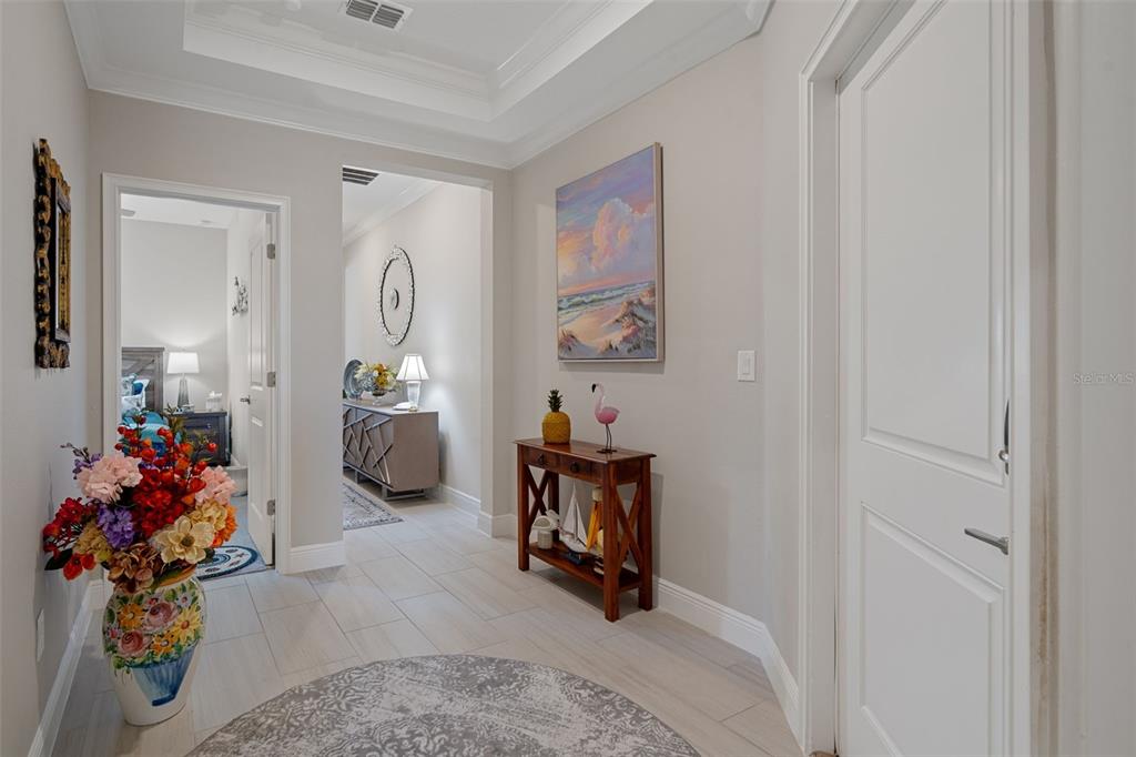 A bright hallway features light tile flooring, a wooden console table, and a colorful painting — 10093 CAMPANULA COURT, LAND O LAKES, FL