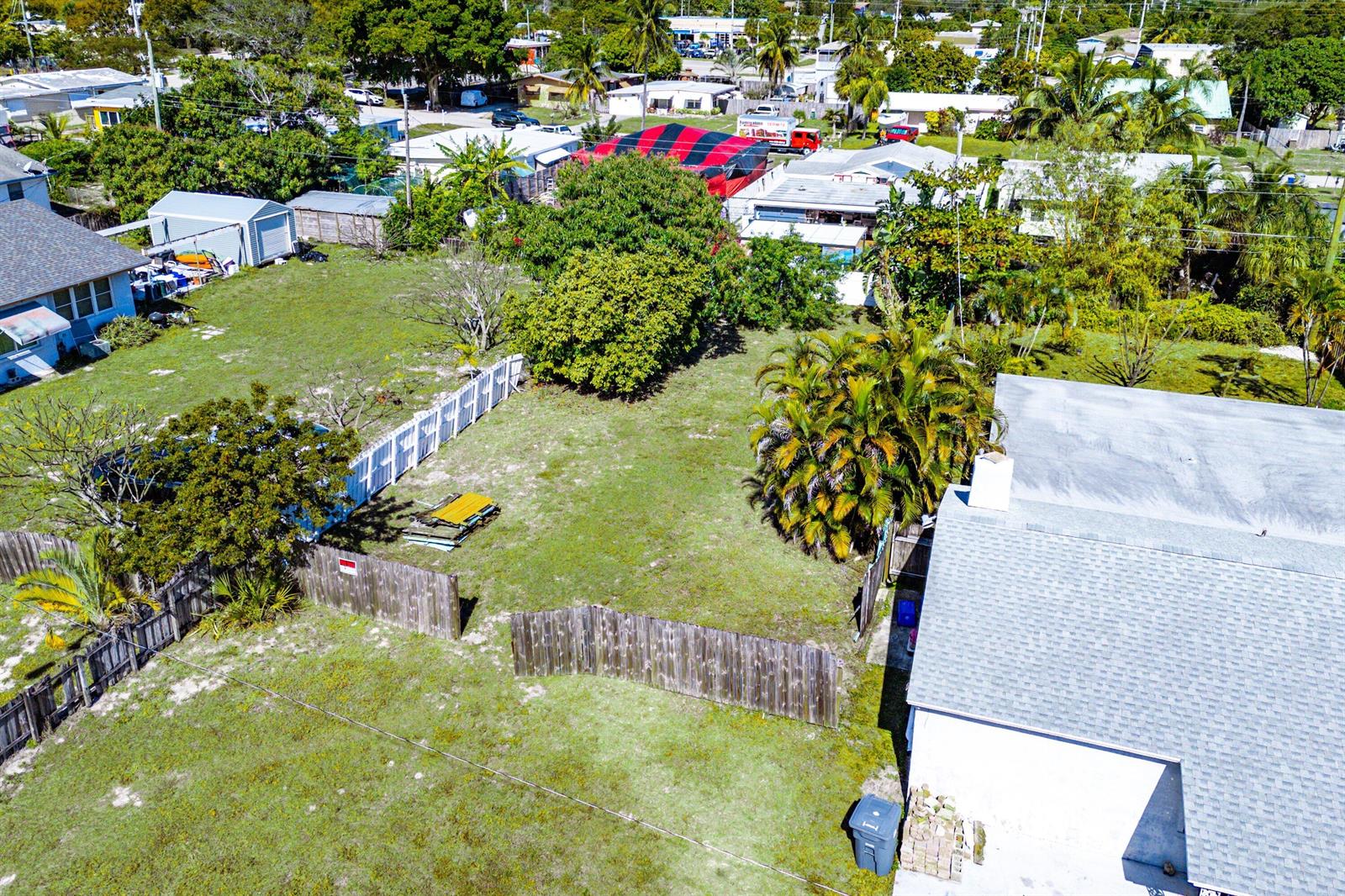 An aerial view shows a grassy residential lot with a wooden fence and nearby houses — 1073 Florence Road, Lake Worth FL 33462, LAKE WORTH, FL