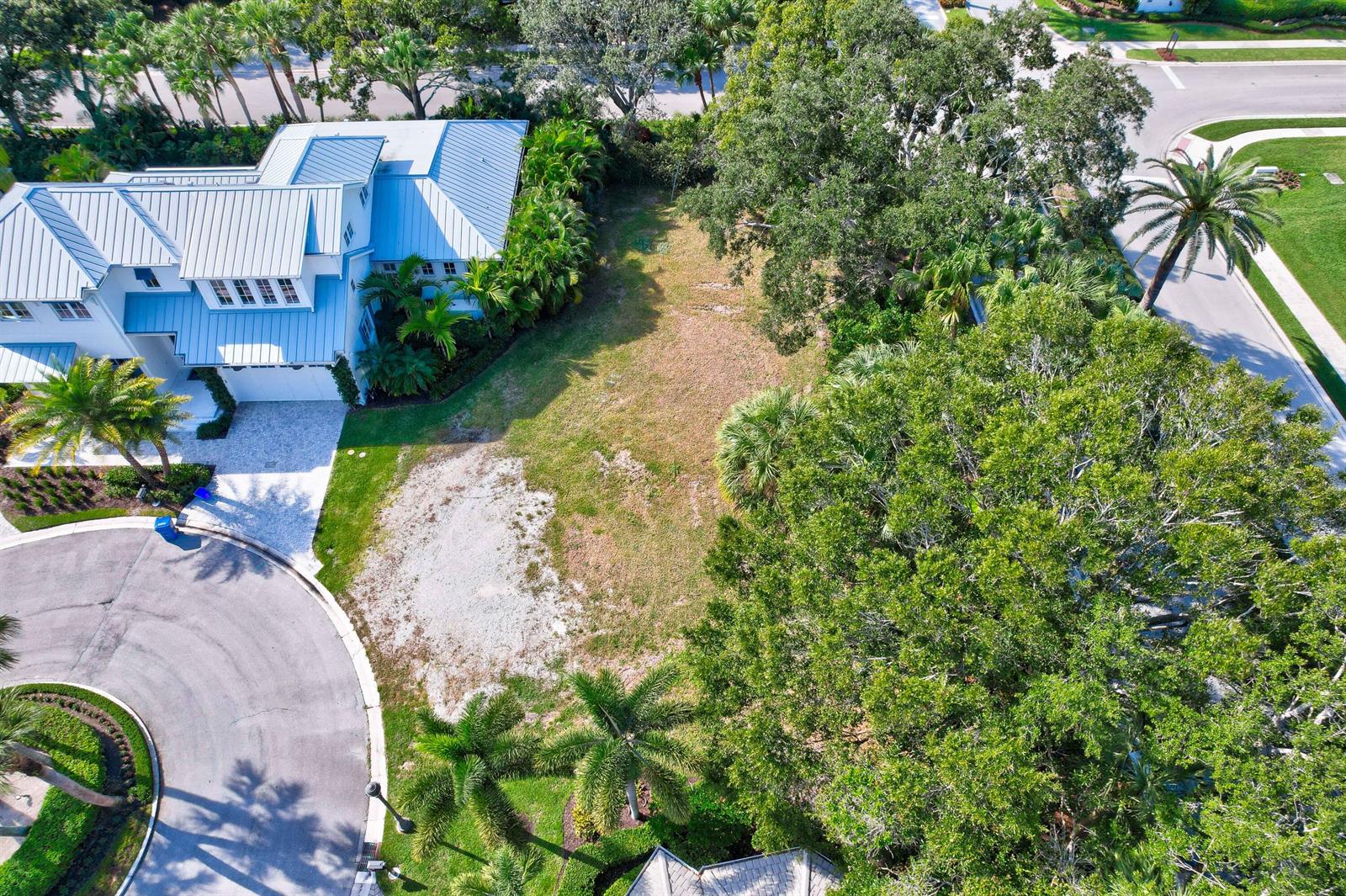 An aerial view shows a vacant residential lot situated between a house and dense trees — 187 Birkdale Lane, Jupiter FL 33458, JUPITER, FL