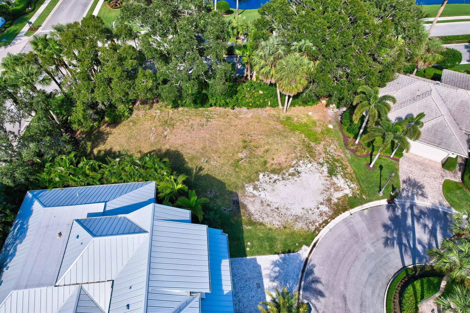 An aerial view shows a vacant residential lot situated between two houses and lush trees — 187 Birkdale Lane, Jupiter FL 33458, JUPITER, FL