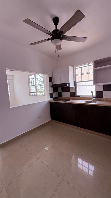 A kitchen with dark cabinets, light countertops, a ceiling fan, and a pass-through window — 413 EDIFICIO GAITHER PLAZA APT. 3A, SAN JUAN, PR