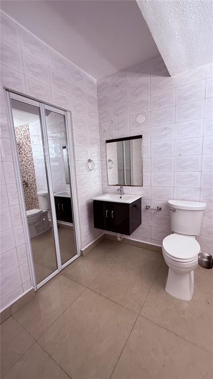A bathroom features white tiled walls, a floating vanity with a mirror, and a toilet — 413 EDIFICIO GAITHER PLAZA APT. 3A, SAN JUAN, PR