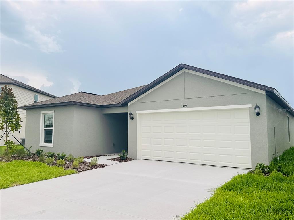 A single-story gray house with a white garage door and a concrete driveway — 869 HOUR GLASS RD, LAKELAND, FL