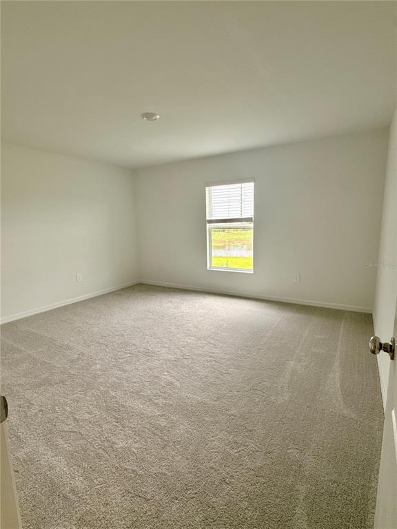 An empty bedroom with beige carpet, white walls, and a single window — 869 HOUR GLASS RD, LAKELAND, FL