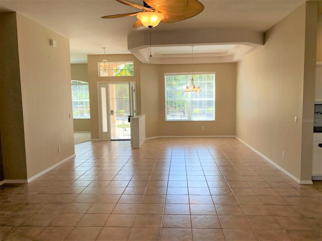 An open-concept dining area features tile flooring, a tray ceiling, and a glass-paned entry door — 4200 TENNYSON WAY, VENICE, FL