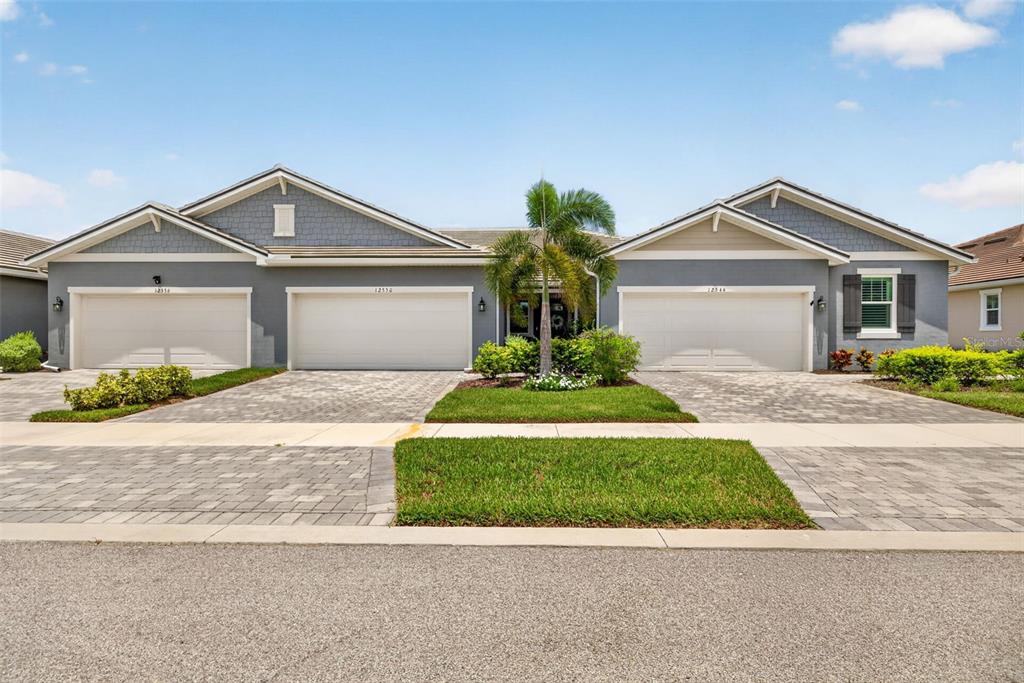 A front exterior view of a multi-unit residential building with three garage doors — 12550 SOMATIC COURT, VENICE, FL