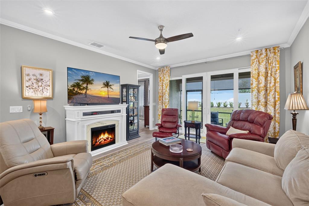 A living room features a fireplace, television, beige sofa, and two red leather recliners — 12550 SOMATIC COURT, VENICE, FL