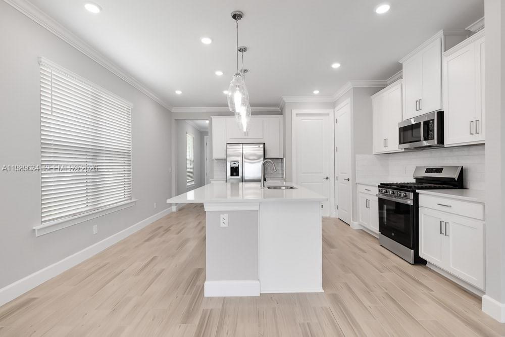 A modern kitchen features white cabinetry, stainless steel appliances, and a central island — 26930 Lark Court, Punta Gorda FL 33955, PUNTA GORDA, FL