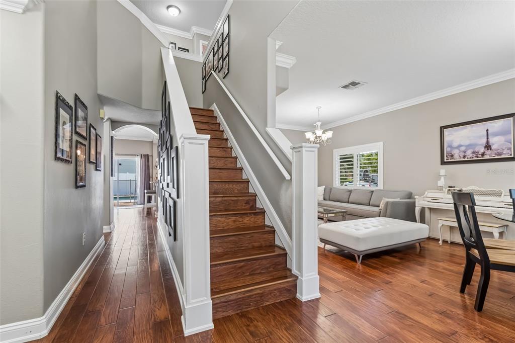 A wooden staircase with white railings stands between a hallway and a living room — 12507 ASHDOWN DRIVE, ODESSA, FL