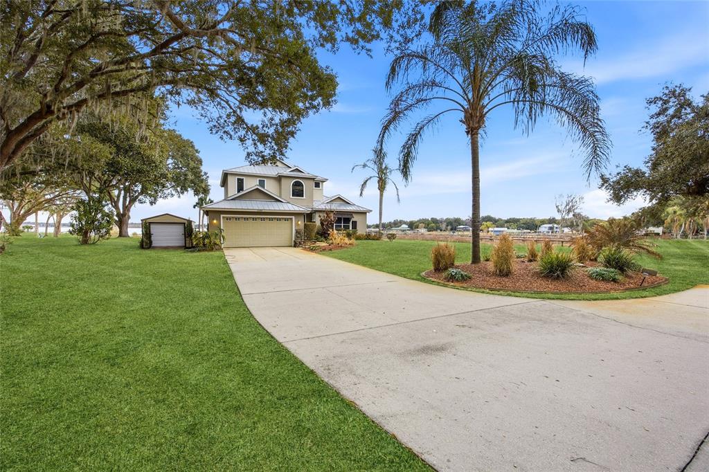 A two-story house with a metal roof and attached garage sits on a grassy lot — 15389 SE 105TH TERRACE ROAD, SUMMERFIELD, FL
