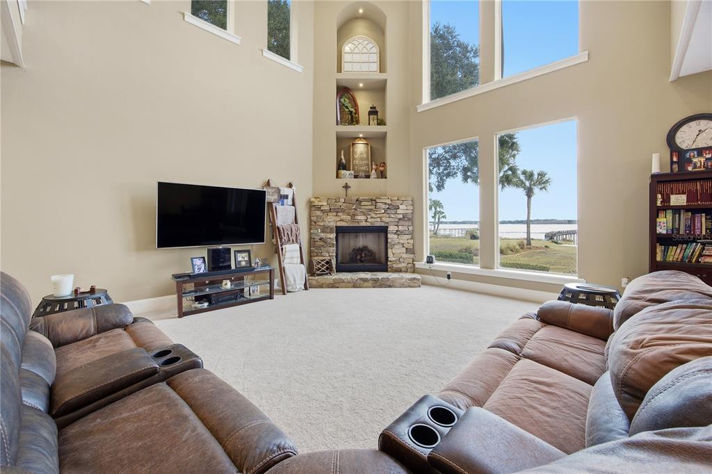 A living room features a stone fireplace, a large sectional sofa, and tall windows — 15389 SE 105TH TERRACE ROAD, SUMMERFIELD, FL