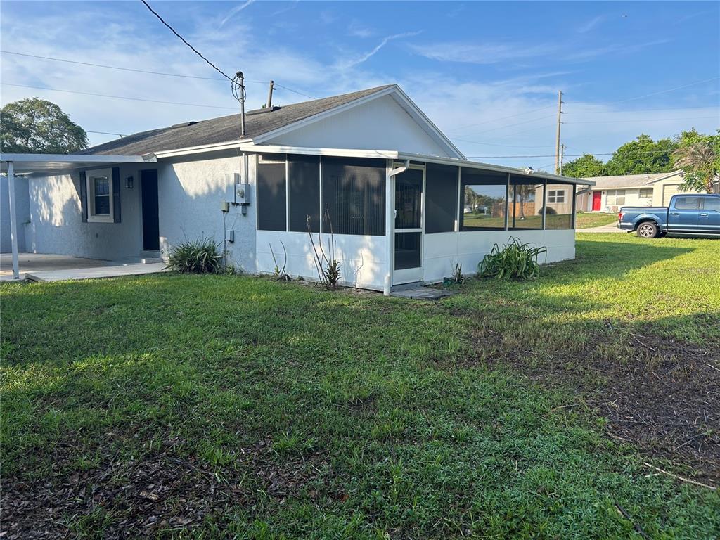A white single-story house features a screened-in porch and a grassy yard — 1450 AGATHA DRIVE, DELTONA, FL