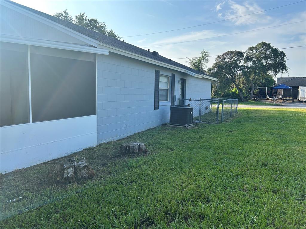 The exterior of a light blue house features a screened-in porch and two tree stumps — 1450 AGATHA DRIVE, DELTONA, FL