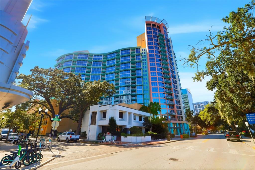 A tall, modern, multi-story apartment building with a curved glass facade stands on a city street — 322 E CENTRAL BOULEVARD UNIT 1109, ORLANDO, FL