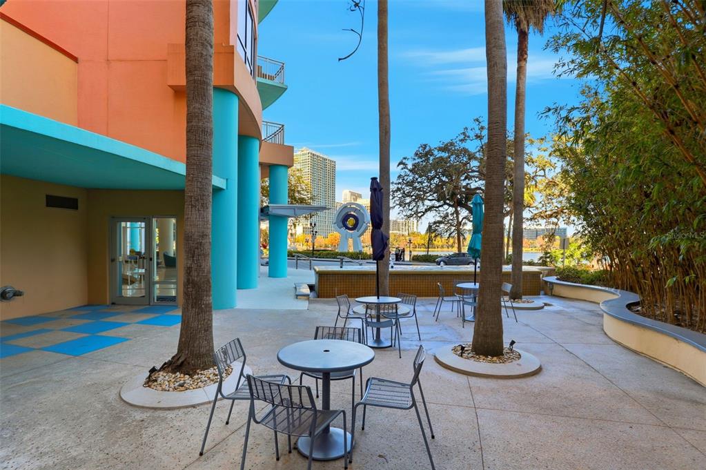 An outdoor patio features metal tables and chairs near palm trees and a building exterior — 322 E CENTRAL BOULEVARD UNIT 1109, ORLANDO, FL