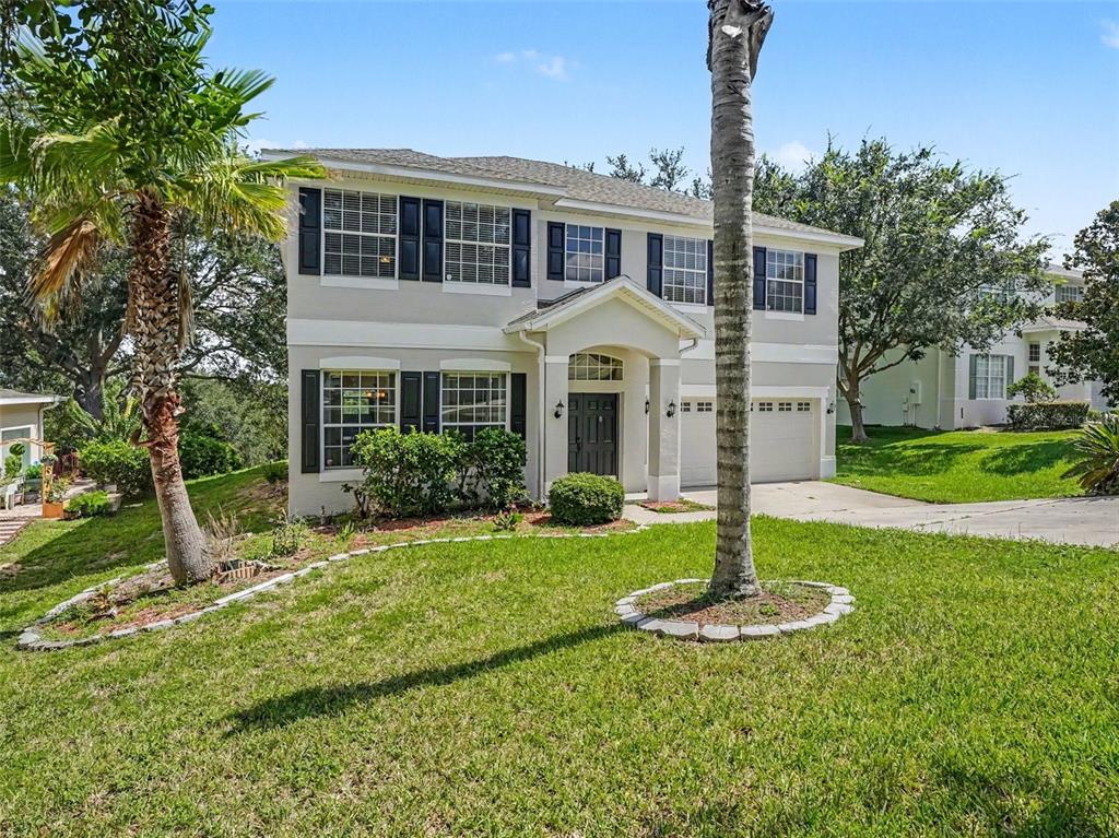 A two-story suburban house with a light-colored exterior, dark shutters, and a front lawn — 1602 PRESIDIO DRIVE, CLERMONT, FL