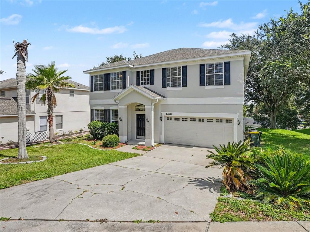 A two-story house with a light-colored exterior, dark shutters, and a concrete driveway — 1602 PRESIDIO DRIVE, CLERMONT, FL