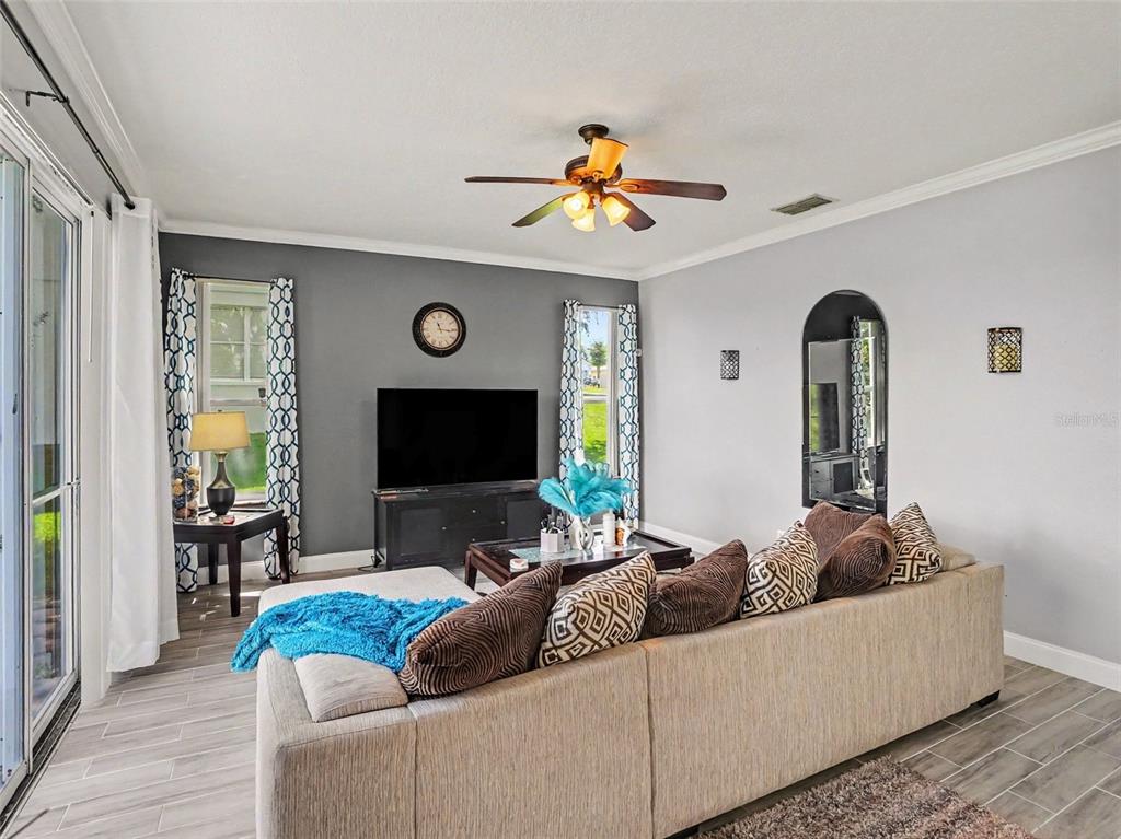 A living room features a sectional sofa, a television on a stand, and gray walls — 1602 PRESIDIO DRIVE, CLERMONT, FL