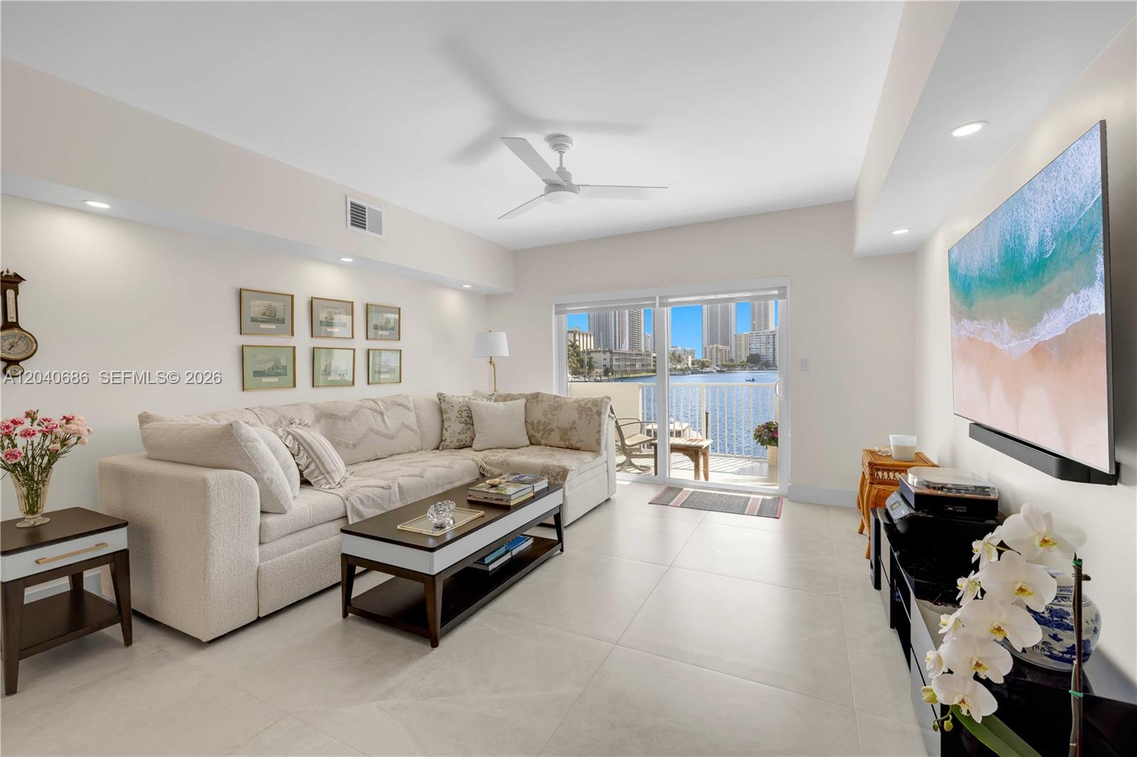 A living room features a sectional sofa, a coffee table, and a balcony overlooking water — 462 Golden Isles Dr # 211, Hallandale Beach FL 33009, HALLANDALE BEACH, FL