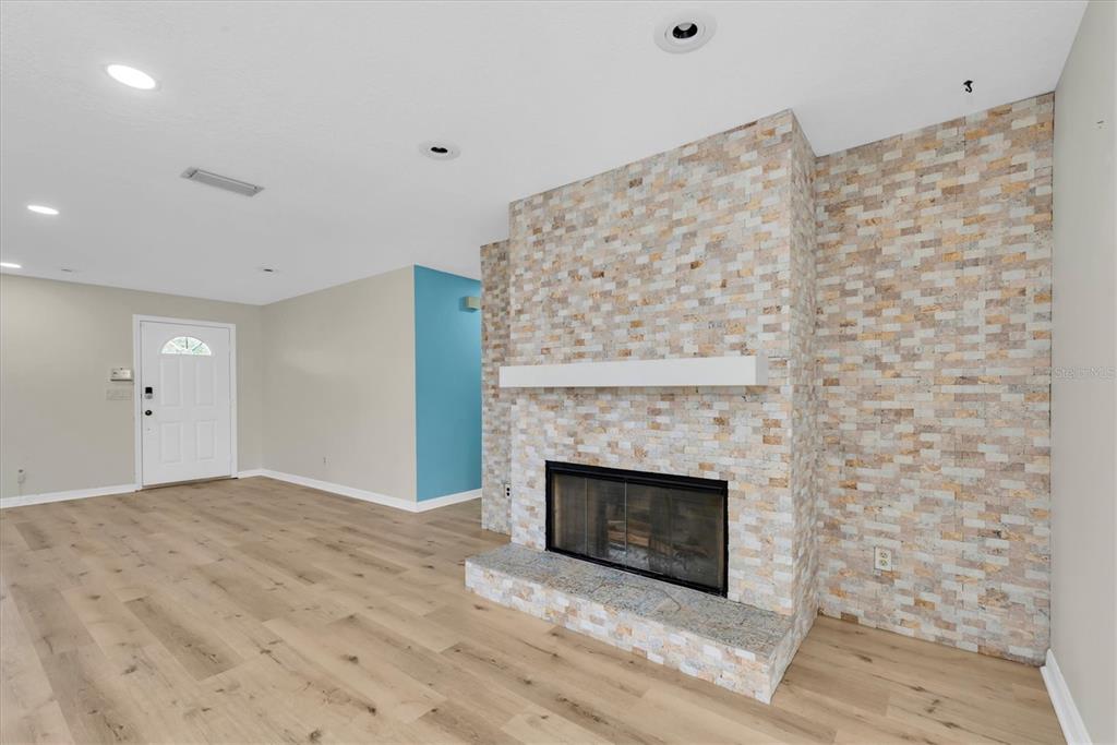 A living room features light wood flooring, a white front door, and a stone fireplace — 13400 91ST AVENUE, SEMINOLE, FL