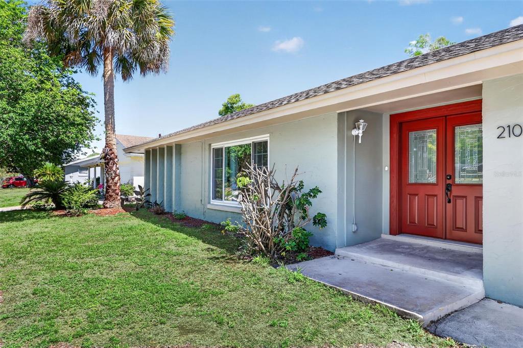 A light green house exterior features a red double front door and a palm tree — 2102 WINNEBEGO TRAIL, FERN PARK, FL