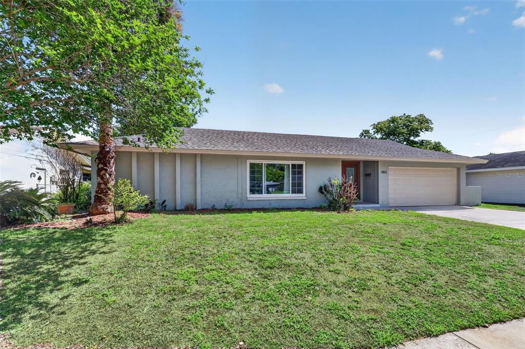 A single-story house with a gray exterior, a two-car garage, and a large front lawn — 2102 WINNEBEGO TRAIL, FERN PARK, FL