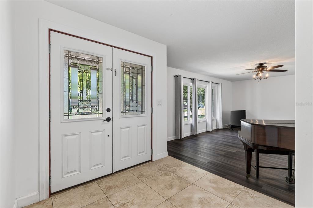 An entryway with tile flooring leads into a living area featuring dark wood-look floors — 2102 WINNEBEGO TRAIL, FERN PARK, FL