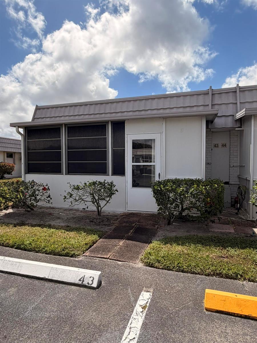 A single-story residential unit with a screened porch, white door, and a numbered parking space — 43 Valencia B, Delray Beach FL 33446, DELRAY BEACH, FL