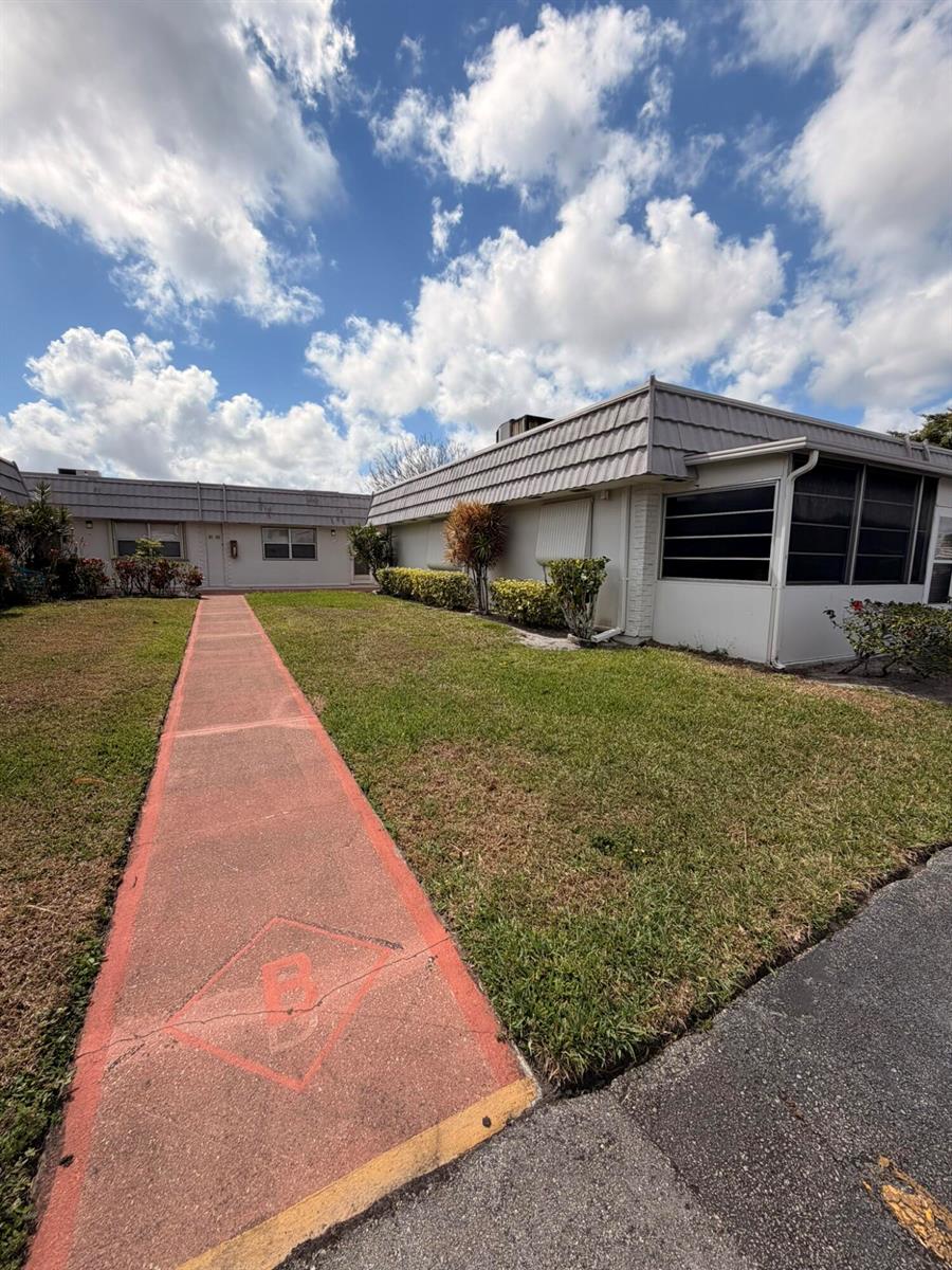 A red concrete walkway leads to the entrance of a single-story building with a screened porch — 43 Valencia B, Delray Beach FL 33446, DELRAY BEACH, FL