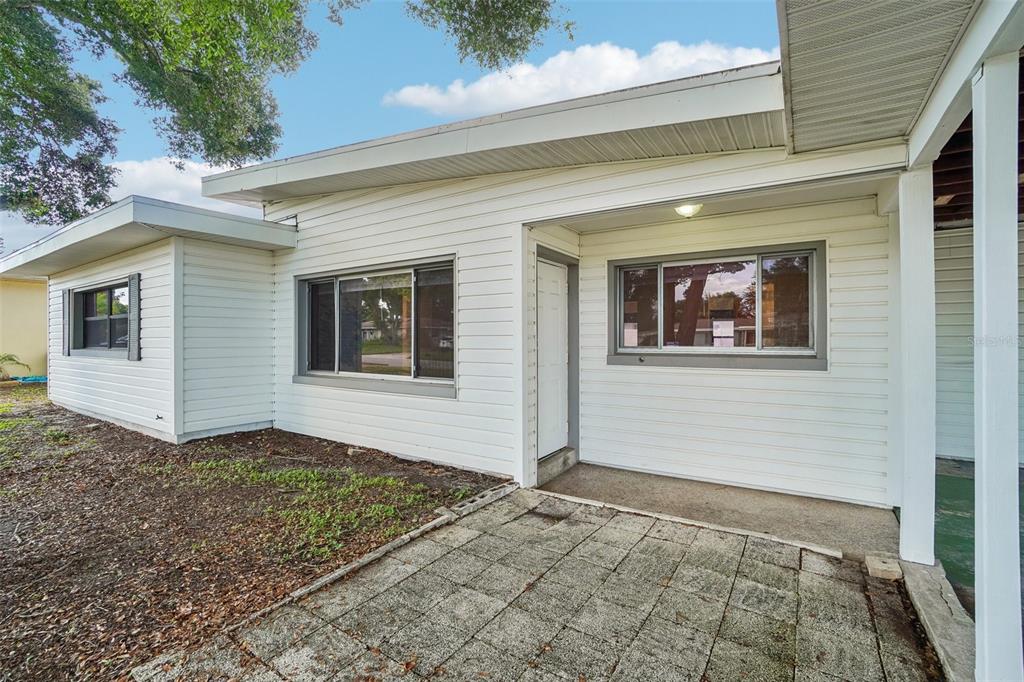 A white-sided house exterior features a paved patio, a front door, and two windows — 1421 TEMPLE STREET, CLEARWATER, FL