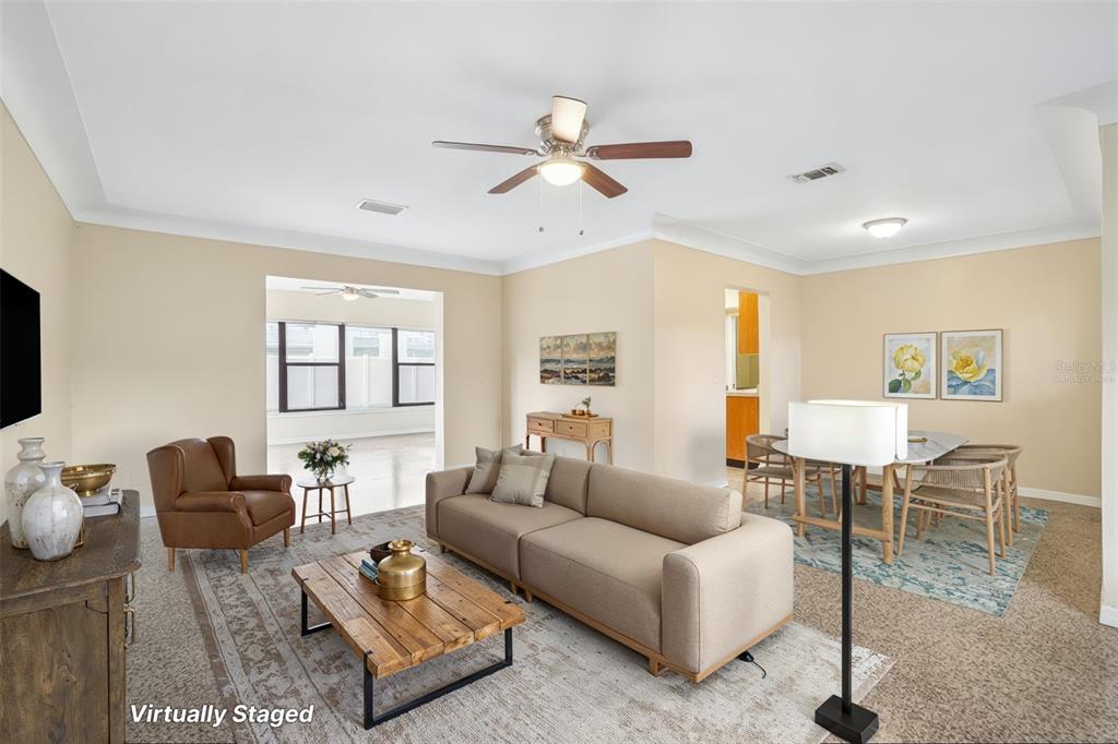 A virtually staged living and dining area with beige walls, a ceiling fan, and carpet — 1421 TEMPLE STREET, CLEARWATER, FL