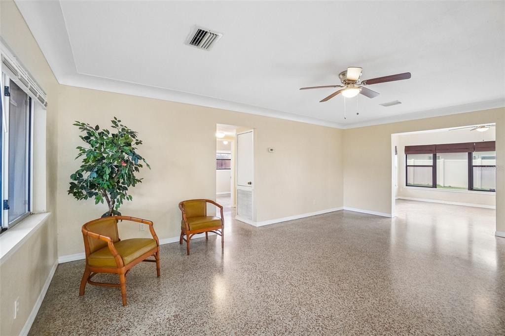 A spacious living room features beige walls, a speckled floor, and two bamboo-style armchairs — 1421 TEMPLE STREET, CLEARWATER, FL