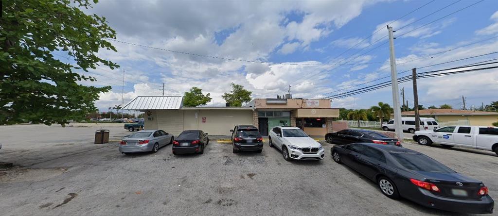 A single-story commercial building with a parking lot in front under a cloudy sky — 19301 NW 2ND AVENUE, MIAMI, FL
