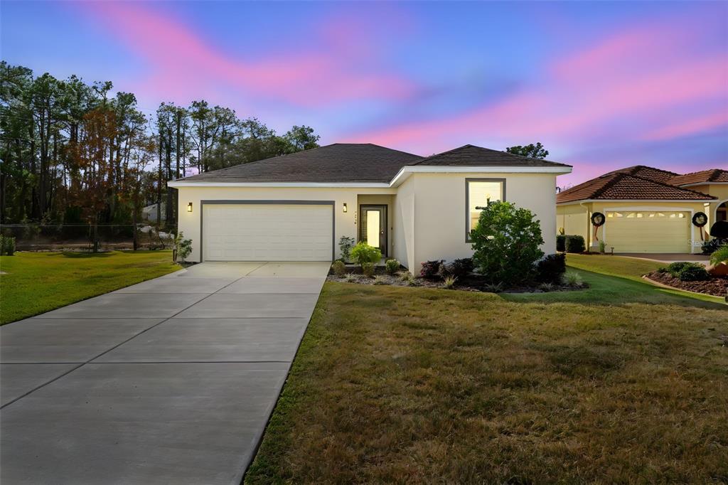 A single-story house with a beige stucco exterior, a two-car garage, and a concrete driveway — 9316 GENTLE BEN COURT, WEEKI WACHEE, FL