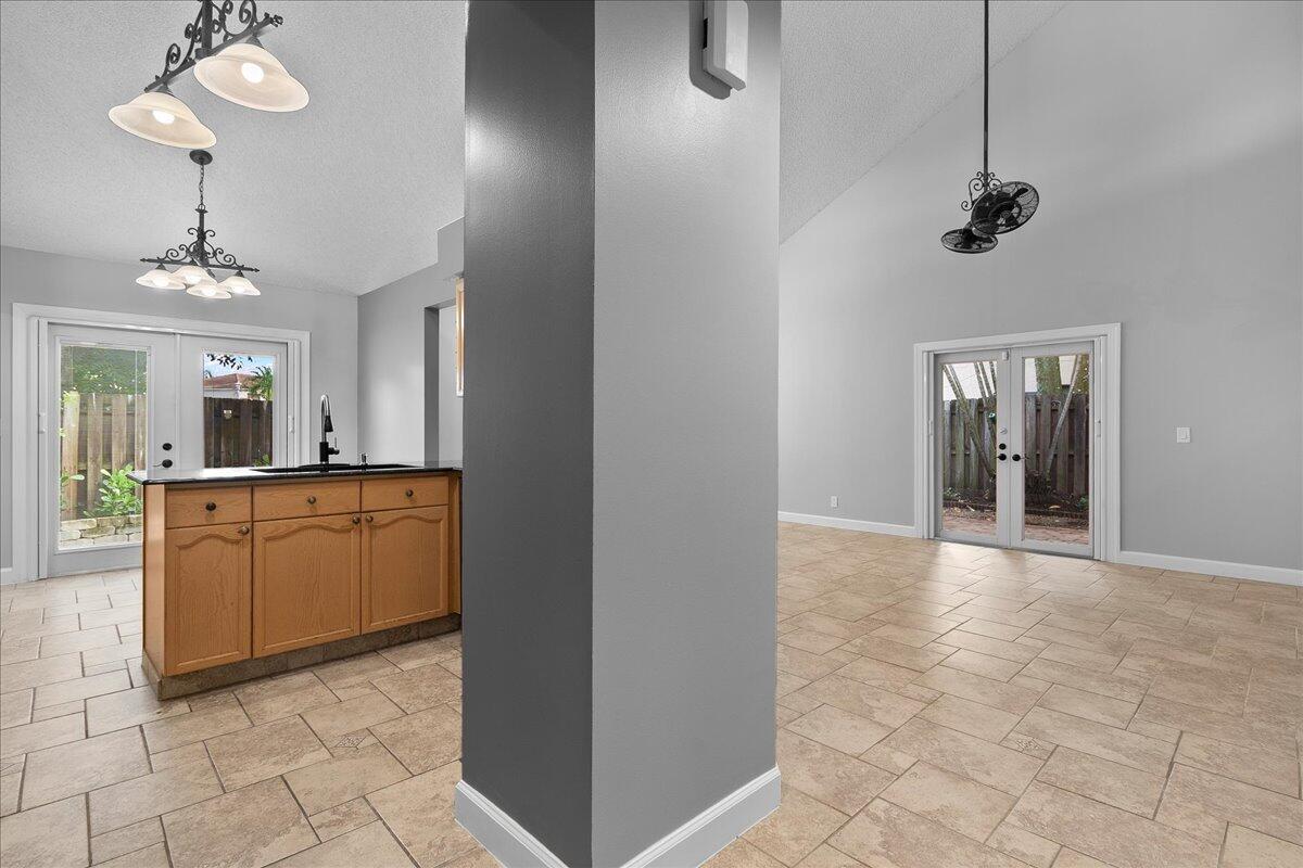 A kitchen island with wood cabinets sits in a room with tile floors and doors — 1714 Shoreside Circle, Wellington FL 33414, WELLINGTON, FL