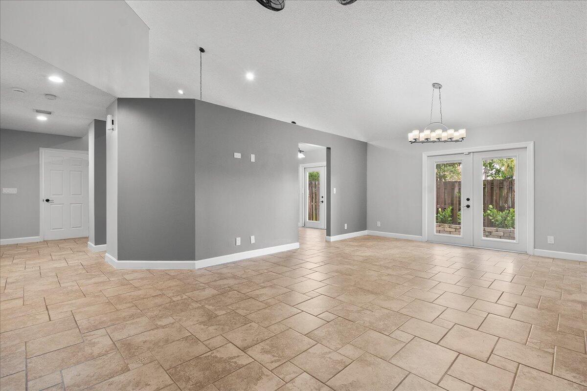 An empty room with gray walls, tile flooring, and French doors leading to a backyard — 1714 Shoreside Circle, Wellington FL 33414, WELLINGTON, FL