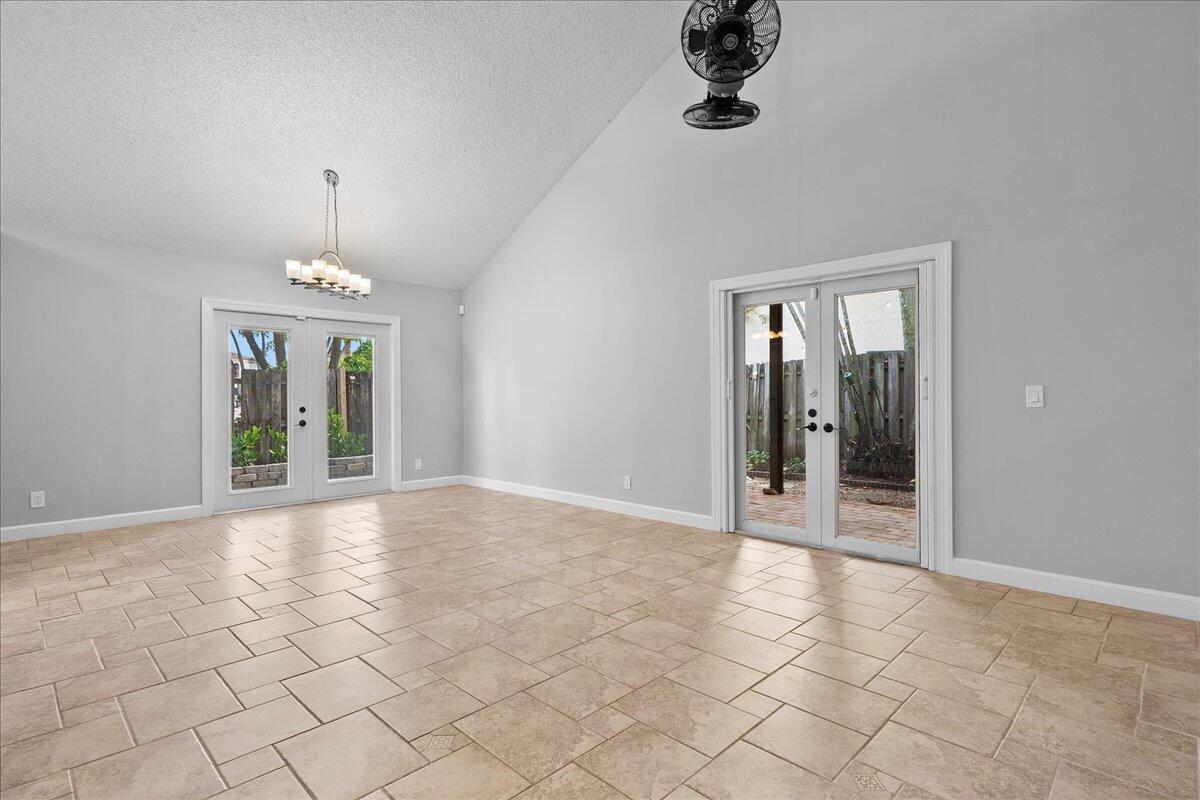 A spacious room with vaulted ceilings, tile flooring, and two sets of glass French doors — 1714 Shoreside Circle, Wellington FL 33414, WELLINGTON, FL