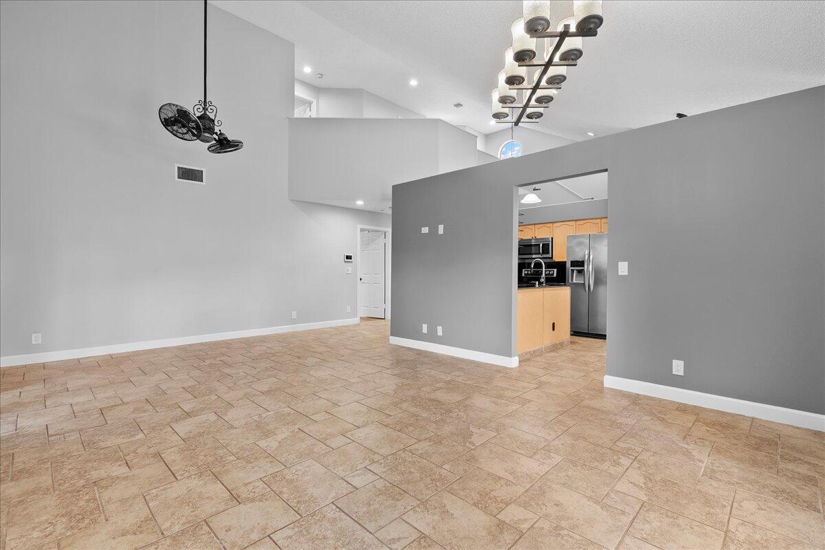 A spacious living area features light tile flooring, vaulted ceilings, and an adjacent kitchen — 1714 Shoreside Circle, Wellington FL 33414, WELLINGTON, FL