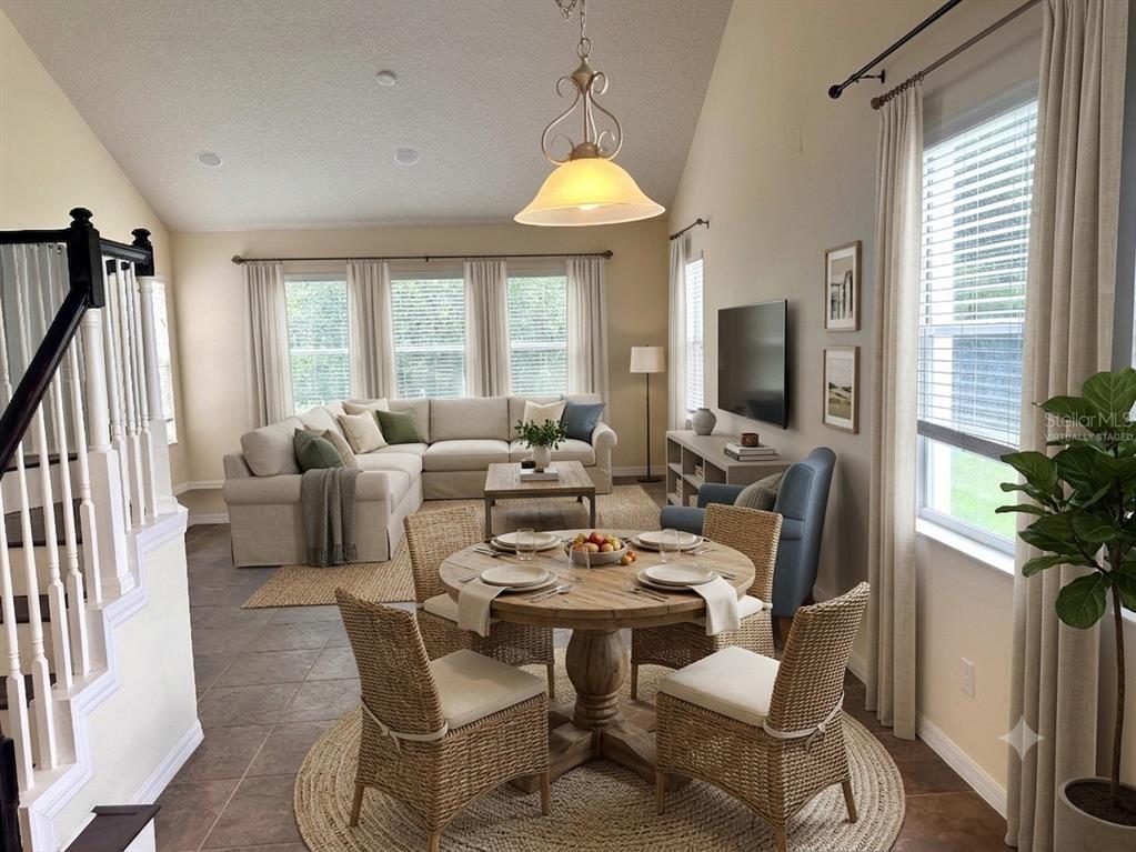 A dining area with a round wooden table sits before a living room with sectional seating — 11773 BELLA MILANO COURT, WINDERMERE, FL
